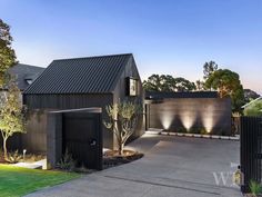 a modern house with black siding and landscaping