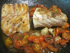 some fish and tomatoes are cooking in a skillet