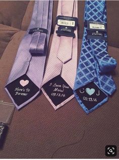 three different colored ties with tags on them sitting on a bed next to each other