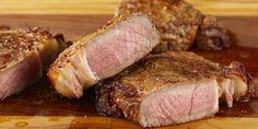 two pieces of meat sitting on top of a wooden cutting board