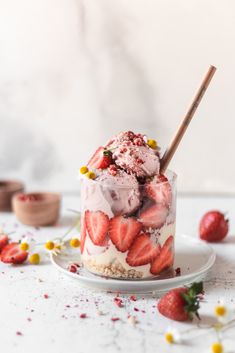 an ice cream sundae with strawberries and whipped cream in it on a white plate