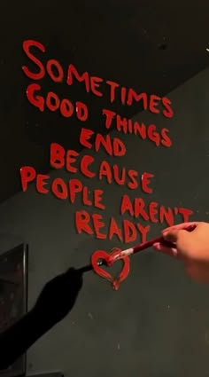 someone is writing something on the wall with red spray paint and there is a knife in their hand