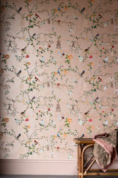 a teddy bear sitting on a bench in front of a wall with flowers and birds