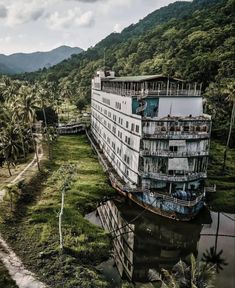 an old building sitting in the middle of a lush green field with palm trees around it