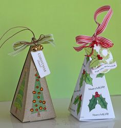 two small christmas trees made out of paper with ribbons and tags on them, sitting next to each other