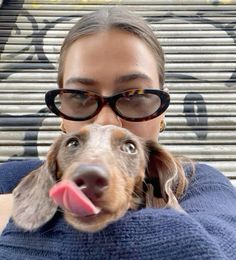 a woman wearing glasses holding a dog in her arms and looking up at the camera