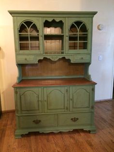 an old green china cabinet with glass doors