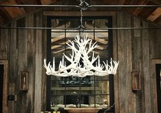 a chandelier hanging from the ceiling in a room with wooden walls and beams