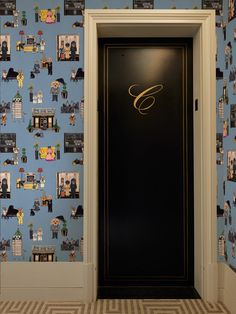 an open door in front of a blue wall with pictures on it and gold lettering