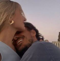 a man and woman embracing each other in front of a building with the sun shining on them