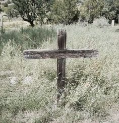 an old wooden cross sitting in the middle of a field