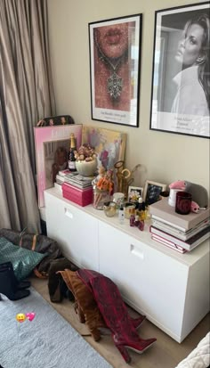 a room with two pictures on the wall and several purses sitting on top of it