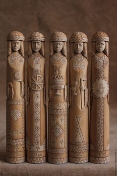 four wooden dolls are lined up in the shape of three people with geometric designs on them