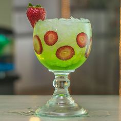 a green drink with strawberries on the rim