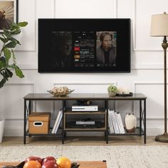 a flat screen tv mounted to the side of a wall next to a table with fruit on it