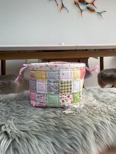 a multicolored patchwork bag sitting on top of a fur rug next to a table