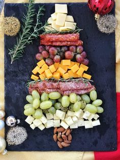 a christmas tree made out of cheese, meat and grapes on a slate platter