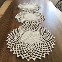 three crocheted doily sitting on top of a wooden table next to a vase