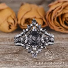 a black diamond ring sitting on top of a wooden table next to some rose petals