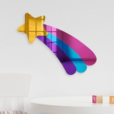 a white table topped with a colorful object next to a wall mounted clock in the shape of an arrow