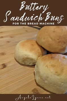 four rolls sitting on top of a wooden cutting board with text overlay reading buttery sandwich buns for the bread machine