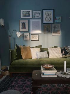 a living room with green couches and pictures on the wall above them, along with a coffee table