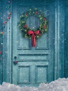 a green door with a wreath on it in the snow