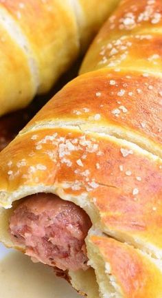 two sausage rolls on a plate with ketchup and mustard