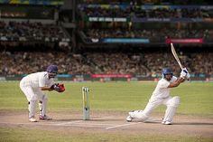 two men in white uniforms playing a game of cricket