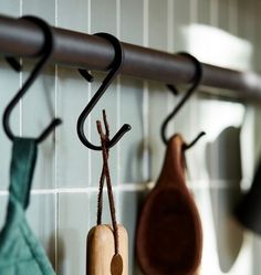 three umbrellas are hanging on the hooks in this kitchen area, one is brown and one is green