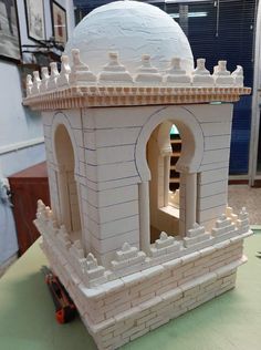 a model of a building made out of white bricks on a table with other items in the background