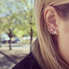 a woman with ear piercings is looking at her cell phone while wearing an earring