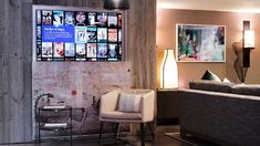 a living room filled with furniture next to a wall covered in posters and pictures on the walls