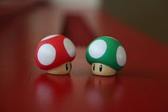 two nintendo mushroom figurines sitting on top of a red table