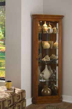 a tall wooden display case filled with vases on top of a hard wood floor