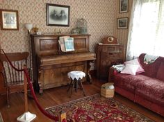 a living room filled with furniture next to a red couch and piano on top of a hard wood floor