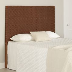 a bed with white sheets and brown headboard