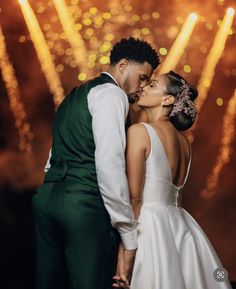 a bride and groom kissing in front of fireworks during their wedding photo shoot at night