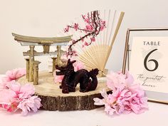 a table topped with pink flowers next to a wooden statue