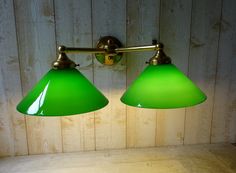 two green lamps are hanging on a wooden wall