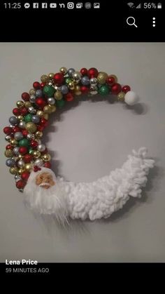 a christmas wreath made out of balls and santa clause's head hanging on the wall