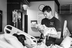 a man standing over a baby in a hospital bed while another woman lays down next to him