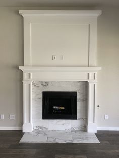 an empty living room with a fireplace and white marble mantles on either side of the fire place