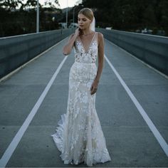 a woman in a wedding dress standing on a bridge