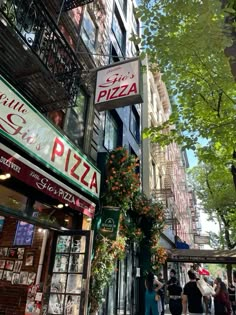 people are walking down the street in front of pizza shops