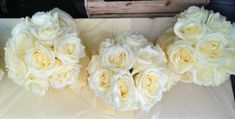 three bouquets of white roses sitting on top of a table