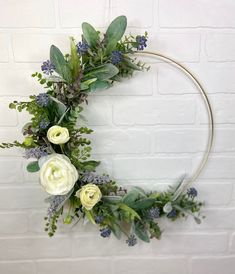 a circular wreath with flowers and greenery hanging on a brick wall