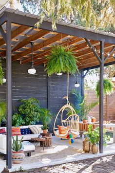 an outdoor living area with plants and hanging chairs in the shade, surrounded by wood planks