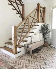 a white couch sitting under a wooden banister next to a stair case on top of a brick floor