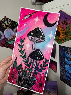 a person holding up a card with mushrooms and stars in the night sky above them